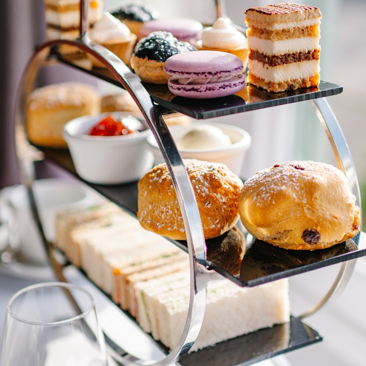 Afternoon tea on a stand with scones, sandwiches and cakes.