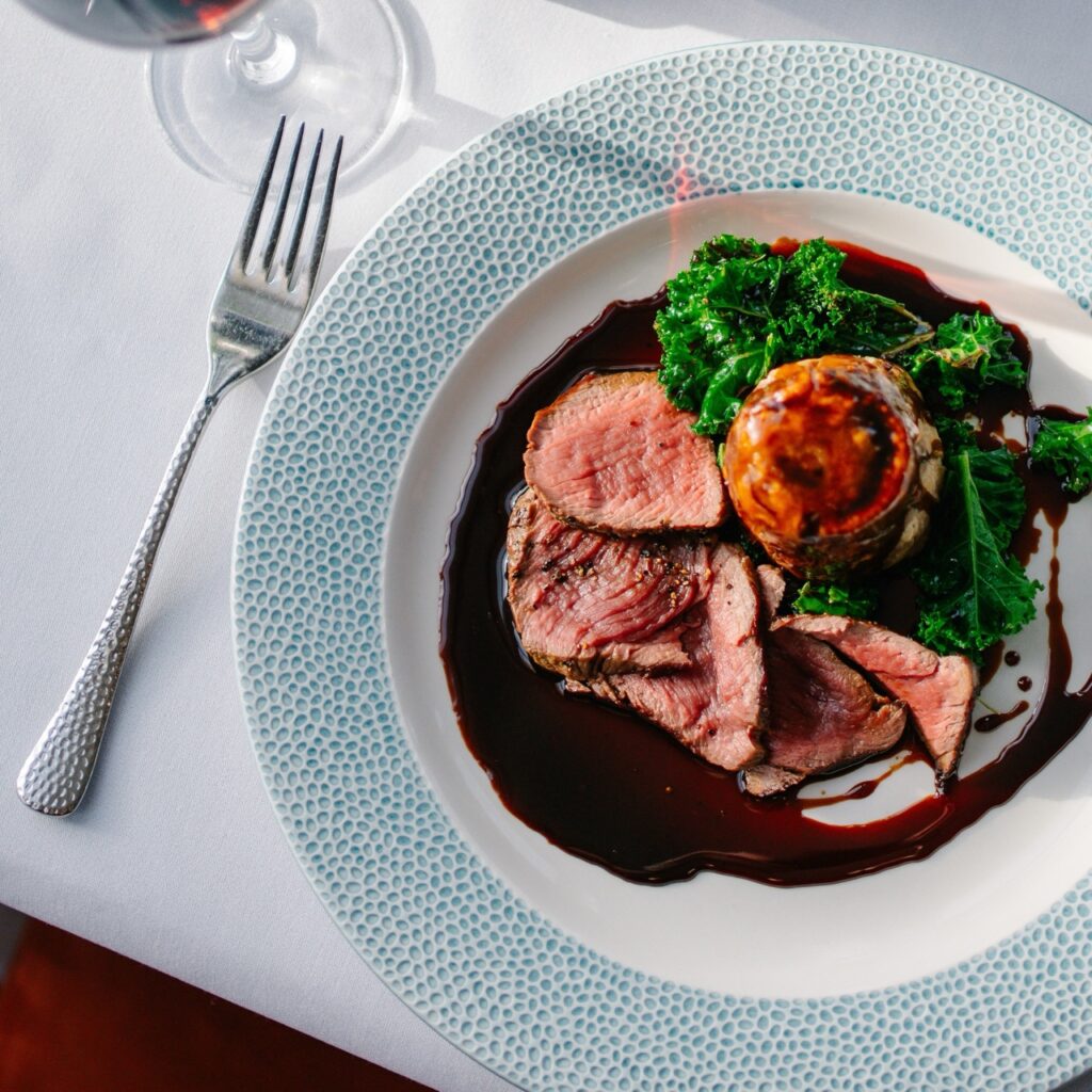 Venison and game suet pudding with greens and gravy served at the tart restaurant at hatton court hotel.